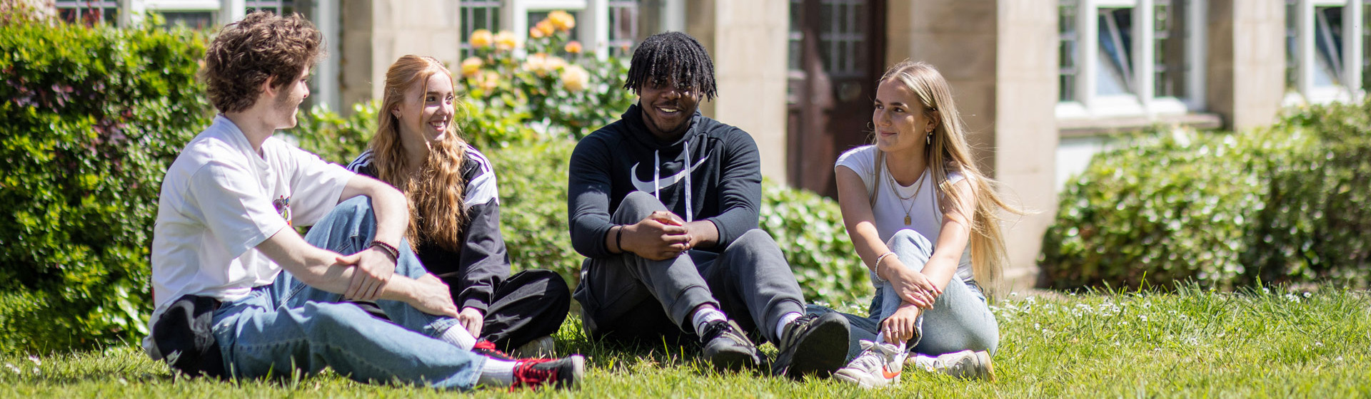 Three students seated on the lawn outside County building